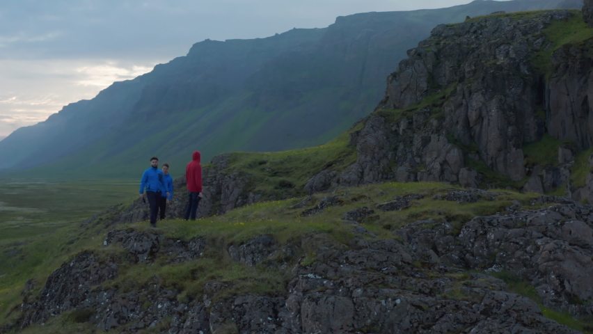 Orbit shot around group of people taking photos of preserved Nordic landscape in morning. Standing on elevated place. Iceland