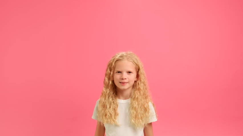 Girl jumping with inscription party. Happy 16-year-old teenage girl in a white T-shirt is having fun at party, holding golden inscription party over her head and jumping, on pink studio background.