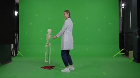 Girl doctor is dancing with skeleton on a Green Screen, Chroma Key.