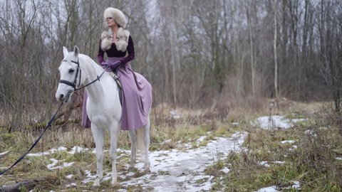 beautiful woman is riding horse in forest in winter, horsewoman is riding in nature