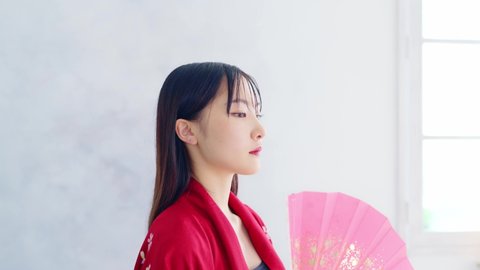 Young Asian woman wearing Japanese Kimono dancing with a fan. Asian fashion concept.