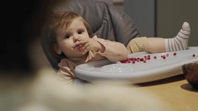 Video with baby had dug into his nose sitting relaxed at the baby table full of grapefruit seeds. Vegetarian food. Healthy food. Organic food.