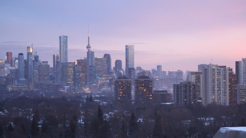Toronto, OntarioCanada: January 17, 2022: City view of downtown landmark and condominium buildings with smokes from heating systems at winter dusk. 