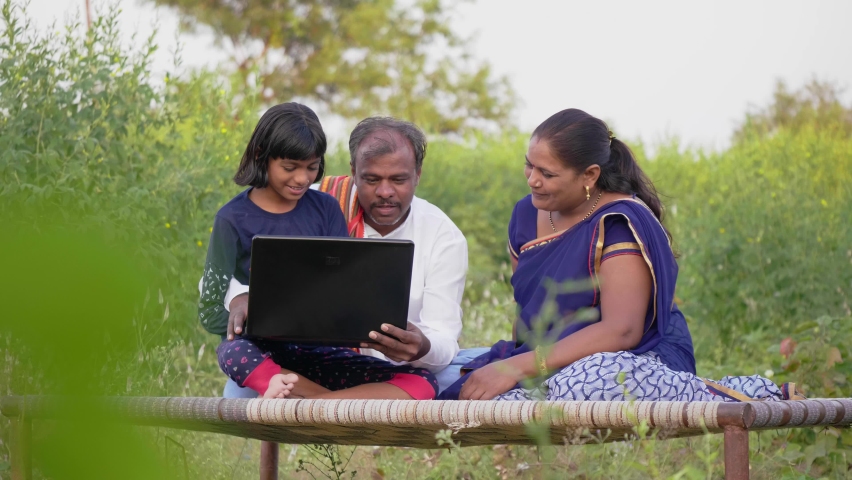 Happy progressive farmer family sitting outdoors on the farm including father, mother, and daughter using a laptop and interacting with each other. Concept of rural Family, relationship and farming Royalty-Free Stock Footage #1085534651