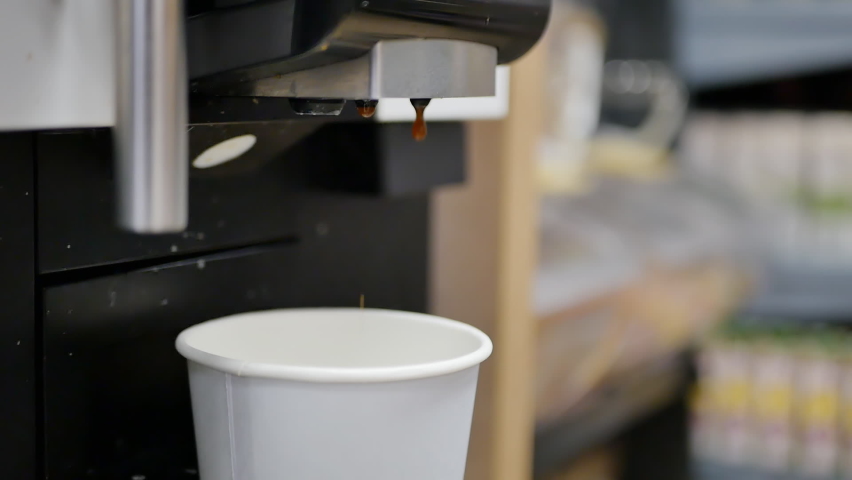Two streams of hot cappuccino are poured into a paper cup in a coffee machine. Aromatic coffee to go for a walk in the open air Royalty-Free Stock Footage #1085534867