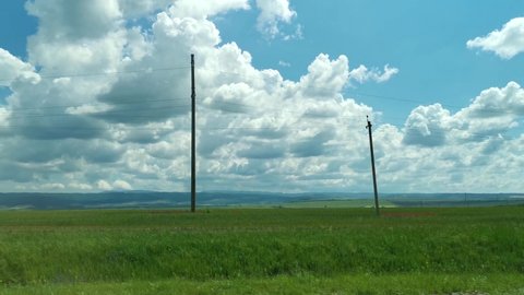 Green fields road car window. View from the side window of the green spring wheat fields and clouds floating across the blue sky. Travel on the roads of Russia, a breathtaking view from the car window