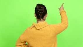 Pretty woman pointing back with the index finger over isolated background. Green screen chroma key