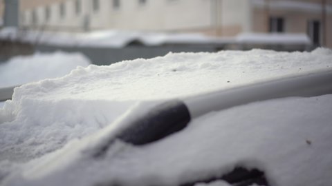 A man cleans the roof of his car from snow with a brush close-up. The car was covered in snow. Weather disaster.