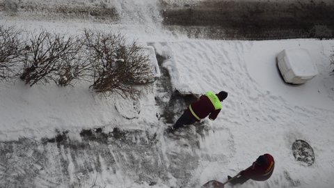 Man janitor removes snow with a shovel on the street