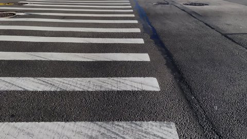 POV a person walks along a crosswalk. Zebra crossing in the city. Asphalt road, people on the street.