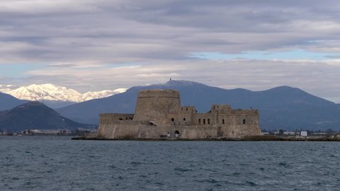 A view of Nafplio surrounded by the sea under a cloudy sky in Gree