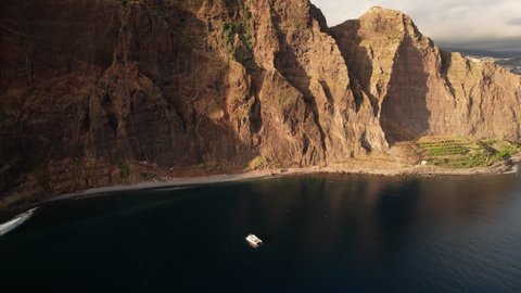 Drone view of lonely catamaran sailing at cliff Cabo Girao, Madeira. Vacation and travel concept