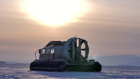 Khuzhir, Russia- March 1, 2021: Hovercraft drives off on snow covered ice surface of Lake Baikal at dusk.