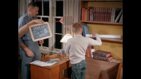 1960s: Man uses pen to gesture at bank book. Man puts bank book in desk drawer. Man and boy unfurl poster. Man holds up cancelled check to lamp.