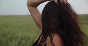 The girl turns her hair in a green field