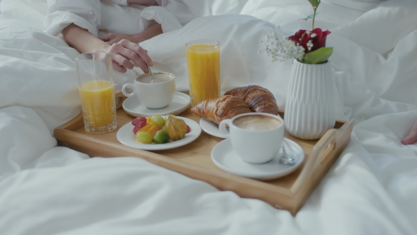 Beautiful Young Ethnic Couple Having Breakfast in Bed With a Tray Full of Food In Front Of Them. Woman Drinking Coffee As She Talks To Her Husband, Spending Valentines Day Together in a Fancy Hotel. Royalty-Free Stock Footage #1085571263