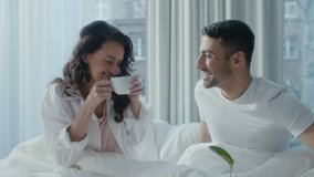 Beautiful Young Ethnic Couple Having Breakfast in Bed With a Tray Full of Food In Front Of Them. Woman Drinking Coffee As She Talks To Her Husband, Spending Valentines Day Together in a Fancy Hotel. - Powered by Shutterstock - Get 15% off with code: PIKWIZARD15