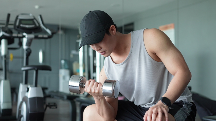 close up young asian man hold dumbbell for gaining bicep muscle arm for weight lifting training and health at gym club in the morning lifestyle concept Royalty-Free Stock Footage #1085571947