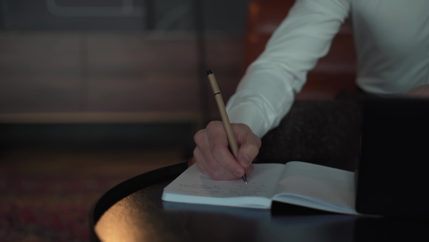 Man writes in a notebook with a pen