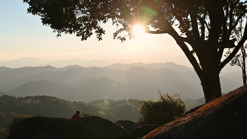 Silhouette hiker man hiking and standing on mountain peak in national park at sunset. Adventure and travel concept