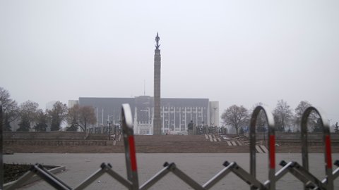 Almaty, Kazakhstan - January 8, 2022: The burnt building of the city administration after the protests in Almaty. City hall after the attack in the fog with a fence in the foreground.