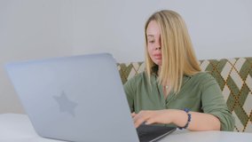 Beautiful young adult woman typing on laptop keyboard in closeup 4k video. White female working freelance on lockdown. Pretty Caucasian person doing distant work online with fast internet connection