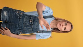 VERTICAL VIDEO POV frowning young blonde woman stop hand gesture decline reject posing isolated on orange. Displeased confident casual informal lady dont want gesturing warning attention advice 