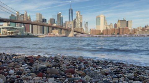 New York city, USA. East river, Brooklyn bridge and downtown Manhattan. View from Dumbo pebble beach. Waves, surf. Stony coastline. Water of sea, ocean, river or lake. Calm and tranquility, meditation