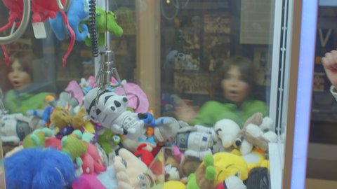 A young father plays with the children claw machine toys. He uses the try, the toy is grabbed and falls. Game failure. CZ, Kladno, Armrnska, 4.11.2021