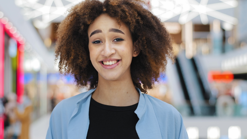 Female portrait happy beautiful african american girl funny woman with curly hair indoors singing song dancing moving to music having fun dances laughing smiling enjoying melody looking at camera