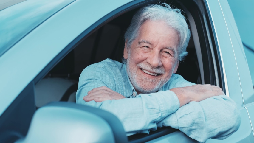 Happy owner looking at the camera with happy face. Handsome bearded mature man sitting relaxed in his newly bought car looking out the window smiling joyfully. One old senior driving and having fun. | Shutterstock HD Video #1085593328