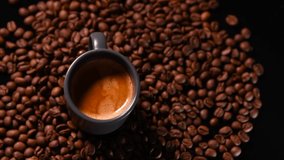 Espresso coffee cup with roasted coffee beans around it filmed from above. 4k video.