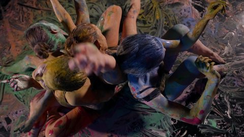 four women covered by dyes are sitting on floor and moving, touching each other
