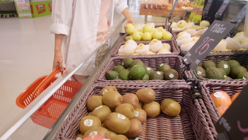 New normal social distancing concept Asian female wearing protective face mask choosing some fruits in supermarket. Women shopping fruit in supermarket during after coronavirus, covid-19 outbreak | Shutterstock HD Video #1085597075