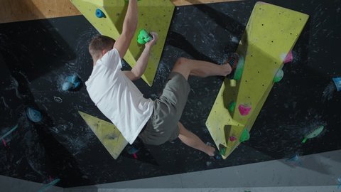 Young climber training on a climbing wall, practicing rock-climbing, mountaineer training, 4k slow motion.