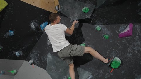 Climber training on a climbing wall, practicing rock-climbing, mountaineer training.