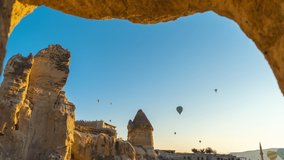 4k stock photography video time lapse of amazing ancient architecture of Cappadocia and many hot air ballons flying in morning sky over buildings and hotels of Goreme town. Turkey