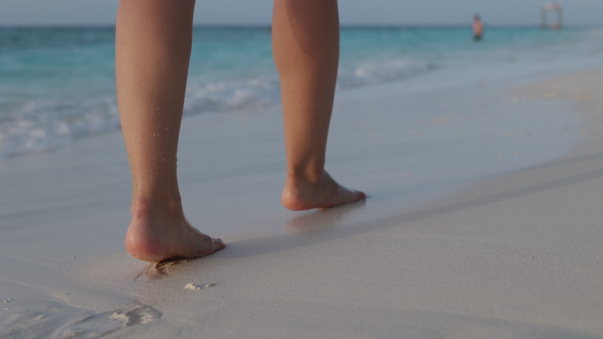 Slow motion of woman feet walking barefoot on the white sand beach at sunset. Female tourist on summer vacation in Maldives. | Shutterstock HD Video #1085607500