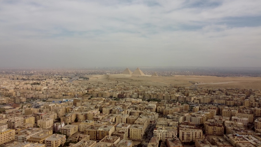 Aerial footage of Cairo city skyline view on a clear day showing Egyptian houses and Giza Pyramids in background. Royalty-Free Stock Footage #1085610377