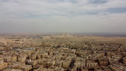 Aerial footage of Cairo city skyline view on a clear day showing Egyptian houses and Giza Pyramids in background.