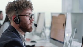 Close Up Portrait of a Technical Customer Support Specialist Talking on a Headset while Working on a Computer in Call center and helpful customer service 24-7. - Powered by Shutterstock - Get 15% off with code: PIKWIZARD15
