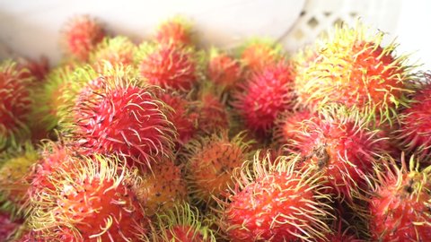 Red rambutan fruit falling in a white basket