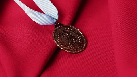 Bronze medal with ribbon on red background close-up. The third place. Award and victory, winning the championship. 