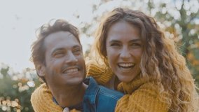 Portrait of happy loving couple with man giving woman piggyback and hugging her in autumn park - shot in slow motion - Powered by Shutterstock - Get 15% off with code: PIKWIZARD15