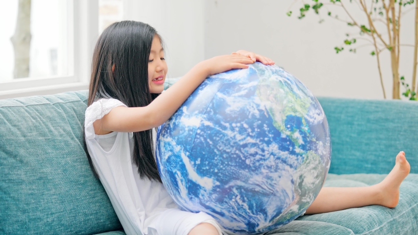 Asian girl playing with a ball with a pattern of the earth.
