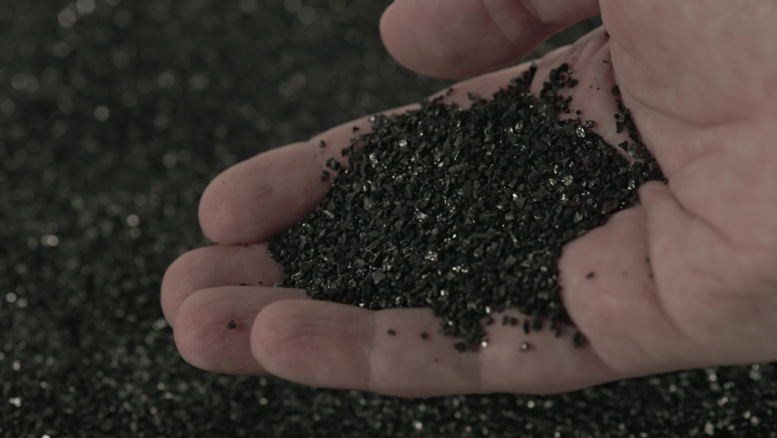 Bare caucasian hand holding and pouring black coconut activated carbon charcoal powder of small fraction in slow motion close-up. | Shutterstock HD Video #1085619008
