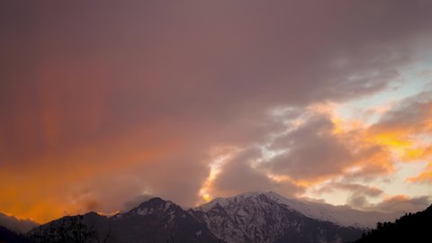 4K Time-lapse of the snow covered mountain during the sunset at Manali in Himachal Pradesh, India. Early morning yellow light hits the peak of the snow covered Himalayan mountain turning it orange.  