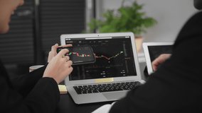 A business man and a woman are sitting at a table, analyzing bitcoin statistics on a laptop. Business people. Close-up - Powered by Shutterstock - Get 15% off with code: PIKWIZARD15