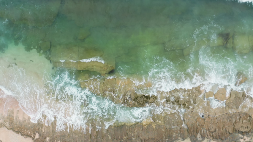  Top shot view of powerful energy and wildlife sea. long shot we go down to a close-up of reef with a wave. Aerial scene with green ocean waves crashing on brown rocks with white foam and splashes.  | Shutterstock HD Video #1085629355