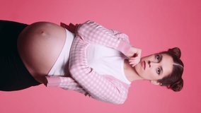 Young beautiful brunette pregnant woman thought about choosing between two different things isolated on pink background. Concept dilemma of choice and doubts for young mother. Vertical video